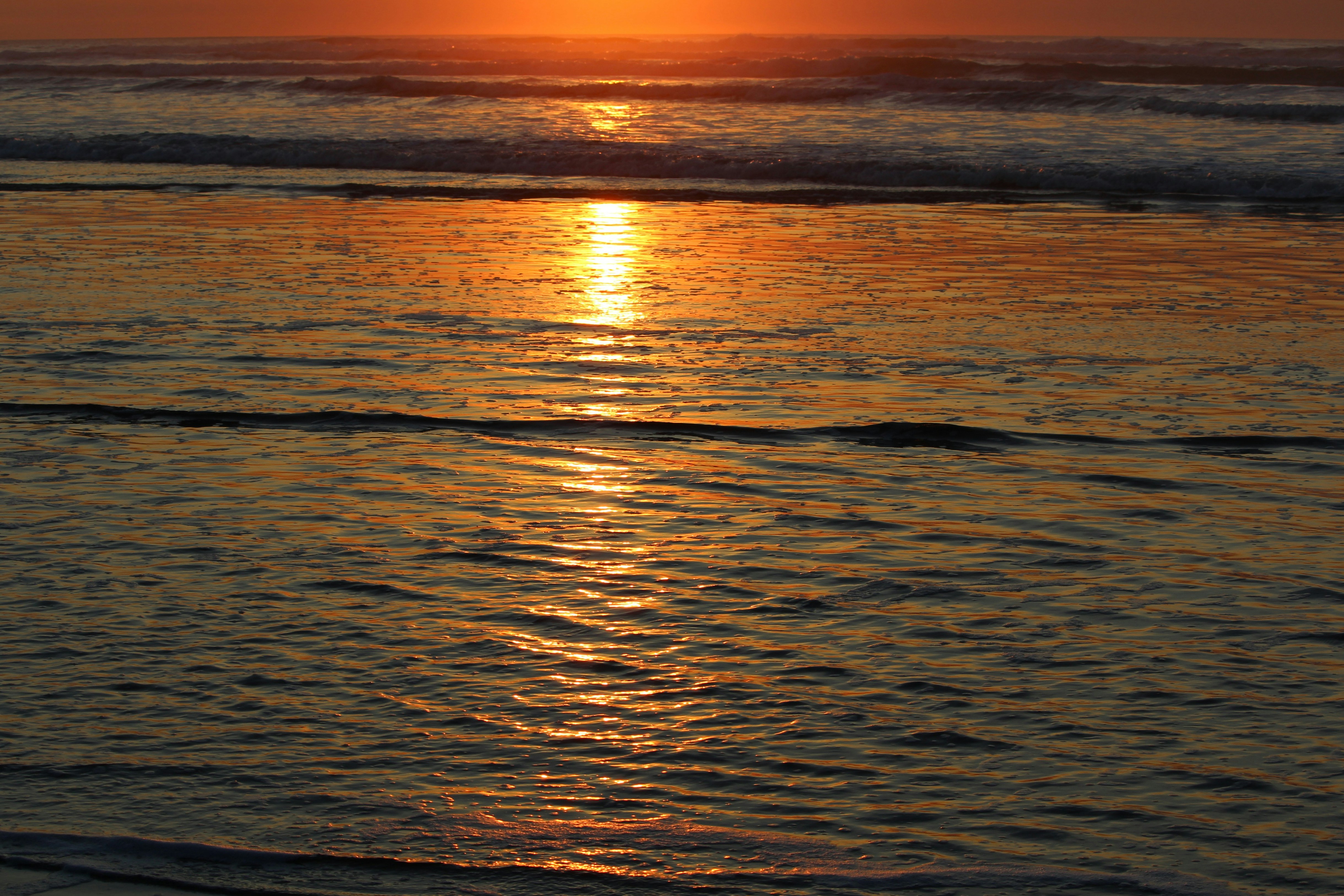 the sun is setting over the water at the beach, 