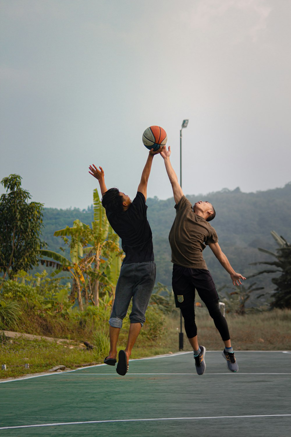 two young men playing basketball on a basketball court