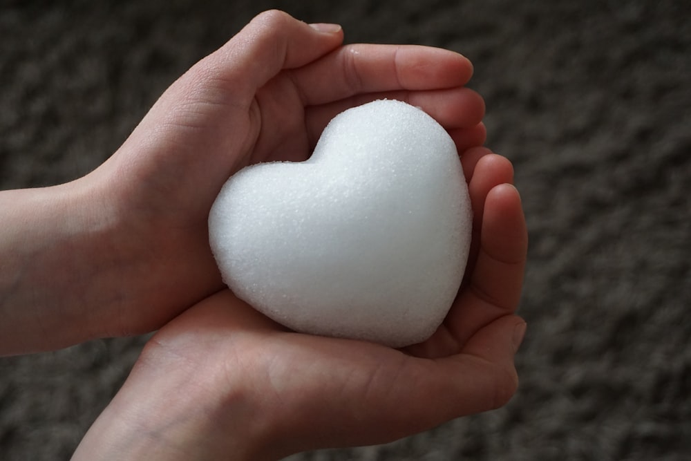 a person holding a white heart in their hands