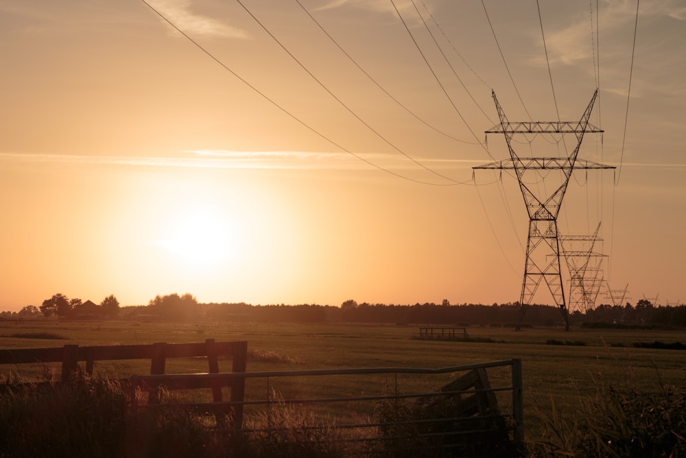 the sun is setting over a field with power lines