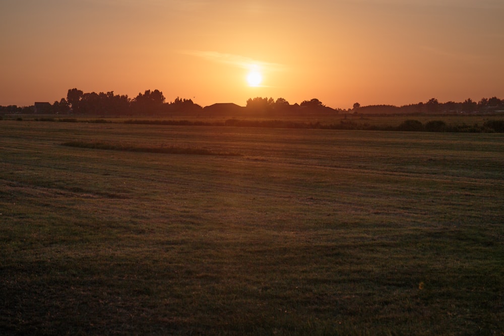 the sun is setting over a field of grass