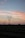 Several transmission towers and power lines stretch across a rural landscape at dusk. The sky displays a gradient of colors from soft pinks and oranges to darker blues, suggesting the setting sun. The land below appears flat with traces of vegetation, silhouetted against the sky.