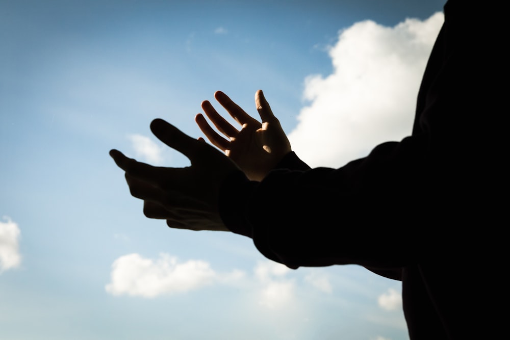 a person holding their hands out in front of a blue sky