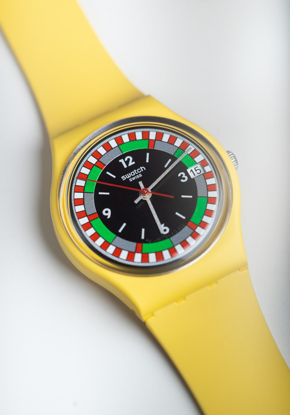 a yellow watch with a black face and green and red numbers