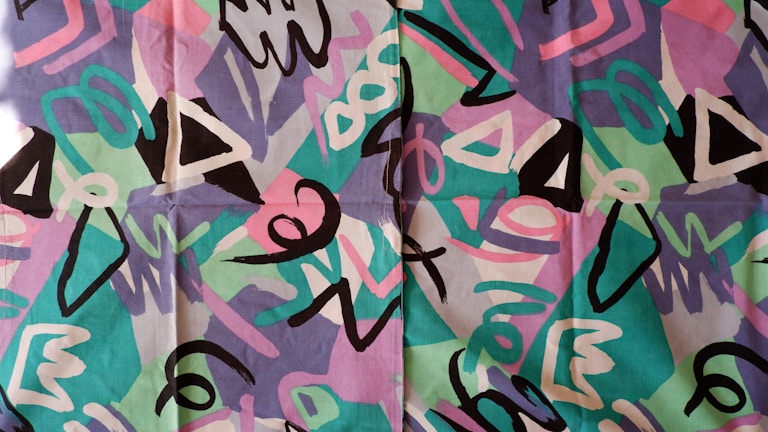 A vibrant graphic tee featuring a colorful abstract pattern on a black background.