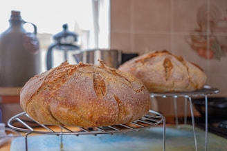 Artisan bread loaves cooling on a rack with a warm kitchen background