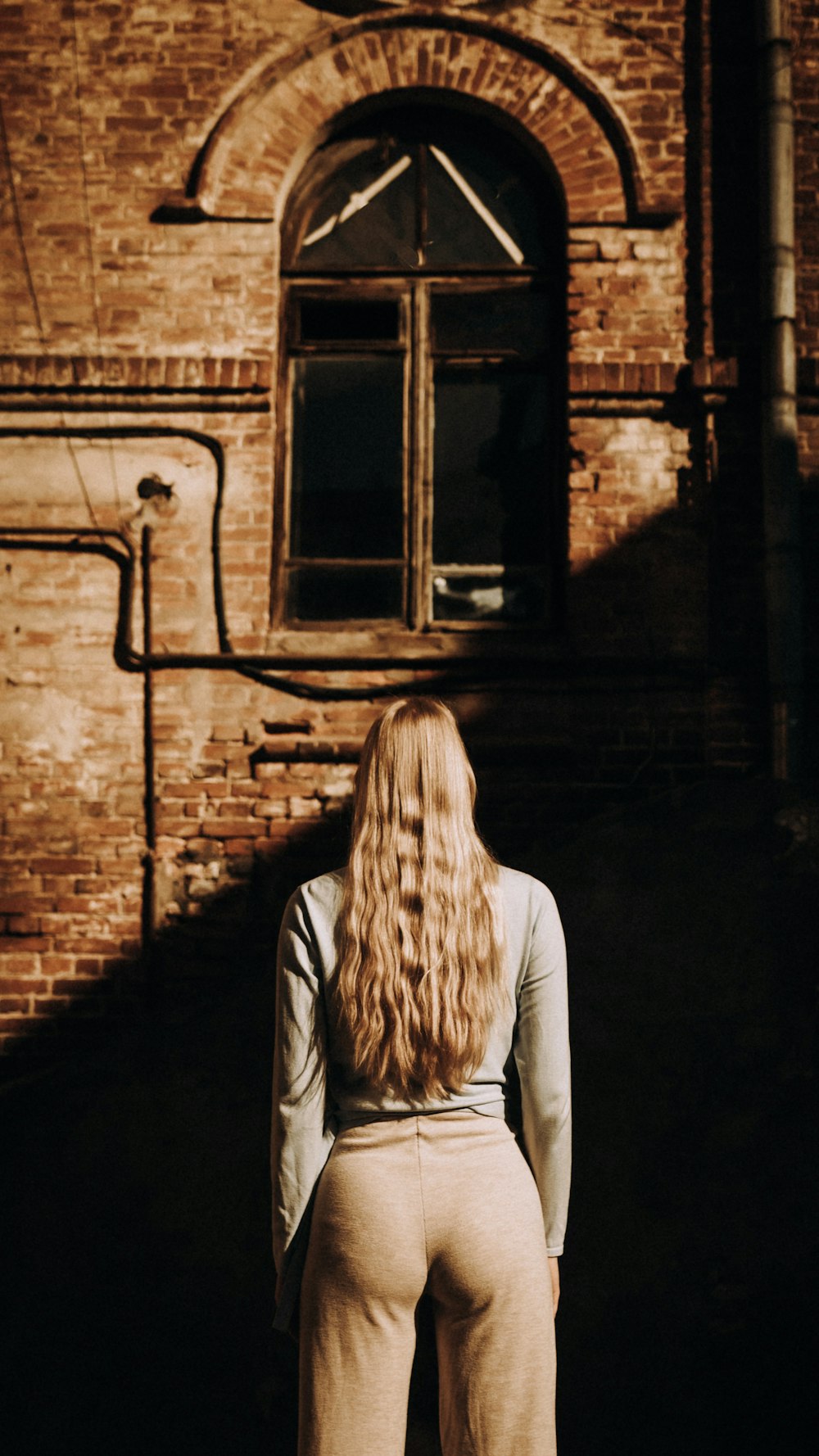 uma mulher em pé na frente de um edifício de tijolos