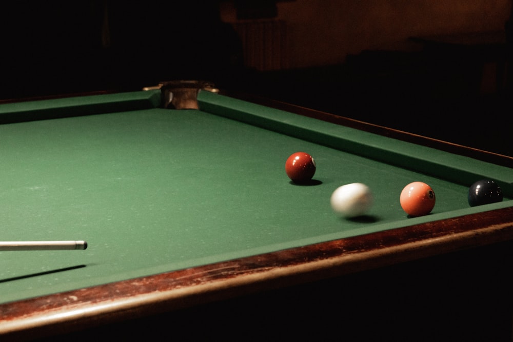 a green pool table with three pool balls on it