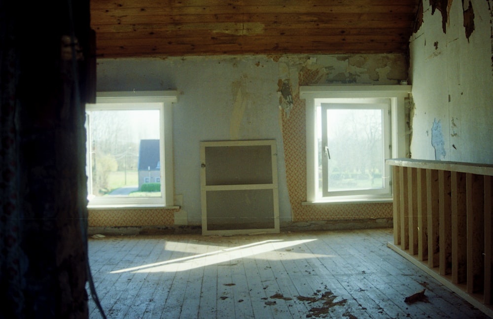 an empty room with two windows and a cabinet