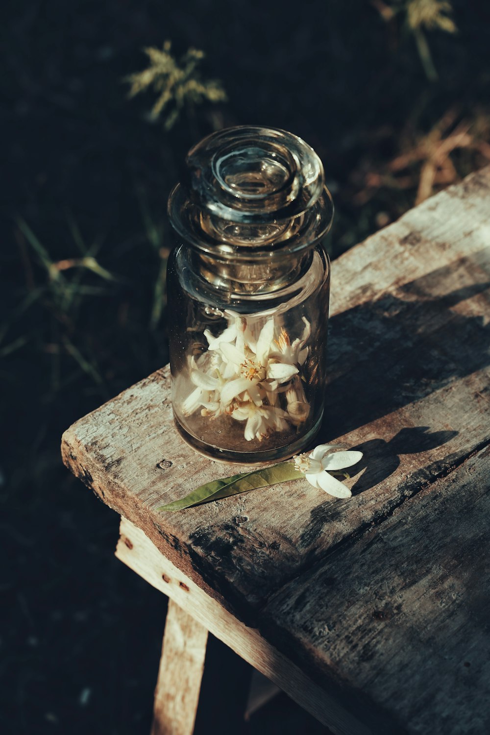 a jar filled with flowers sitting on top of a wooden table