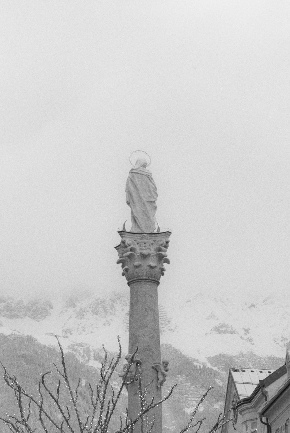 a black and white photo of a statue on top of a building