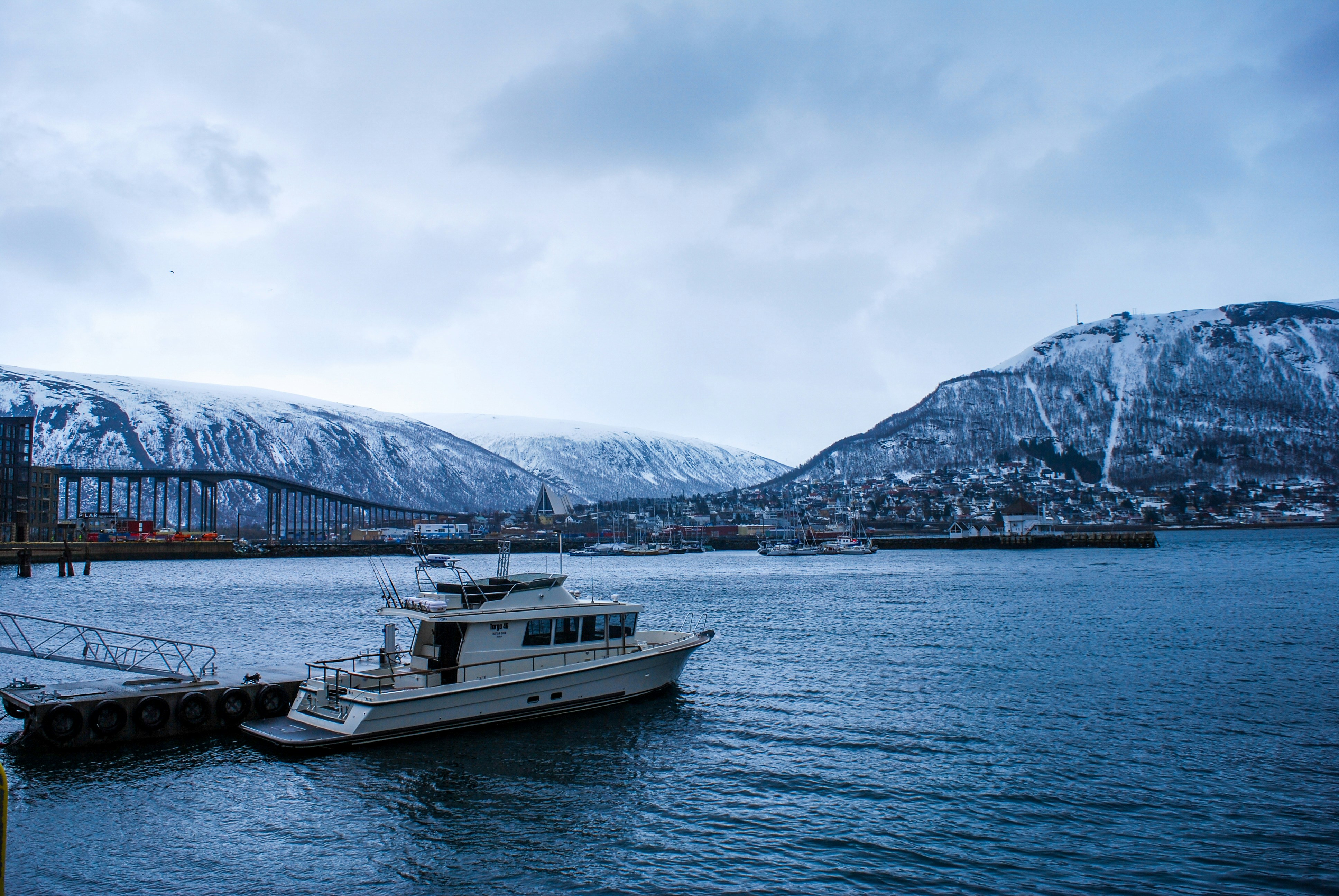 a boat is docked at a pier in the water, Tromso fjord.