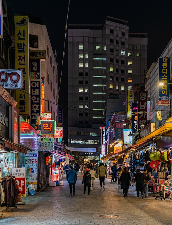 a group of people walking down a street next to tall buildings