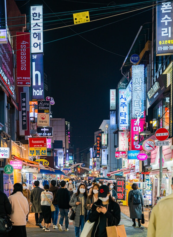 a group of people walking down a street at night