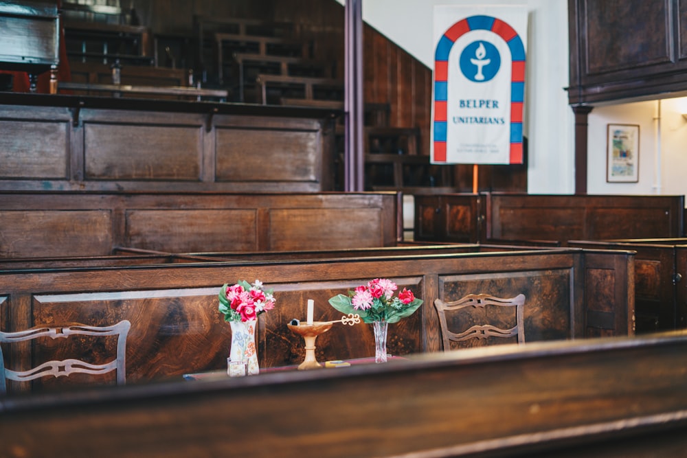 two vases of flowers sit on the pews of a church