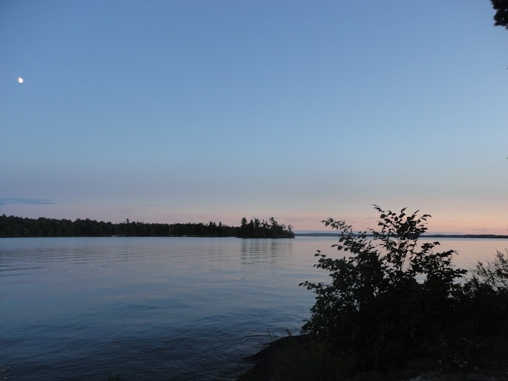 a full moon is seen over a lake