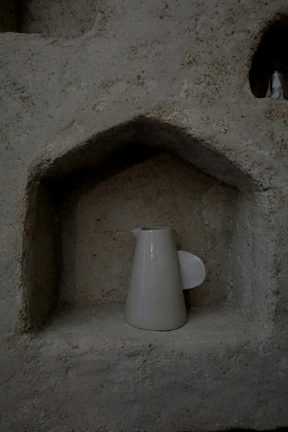 a white vase sitting inside of a stone wall