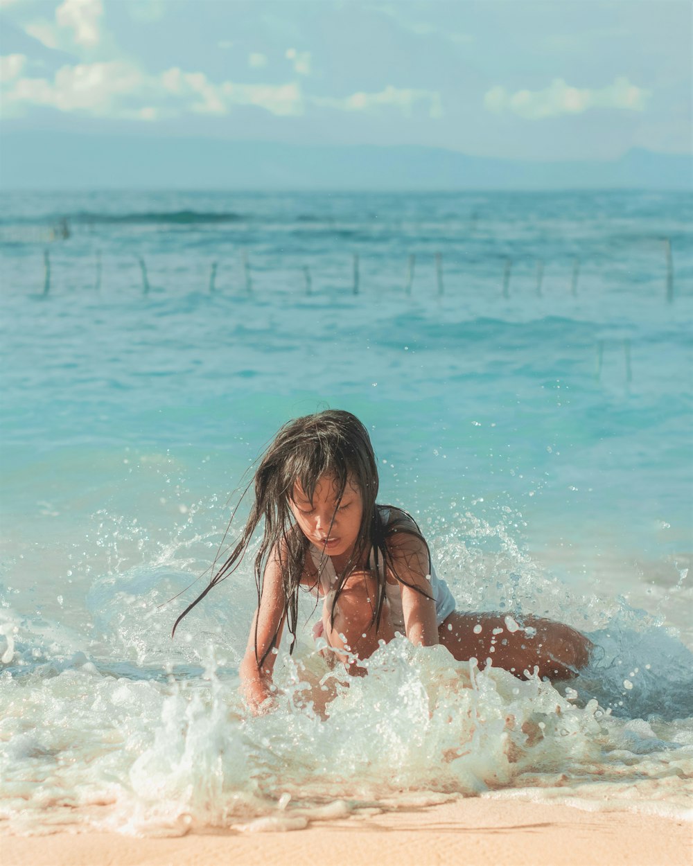 a little girl is playing in the water at the beach