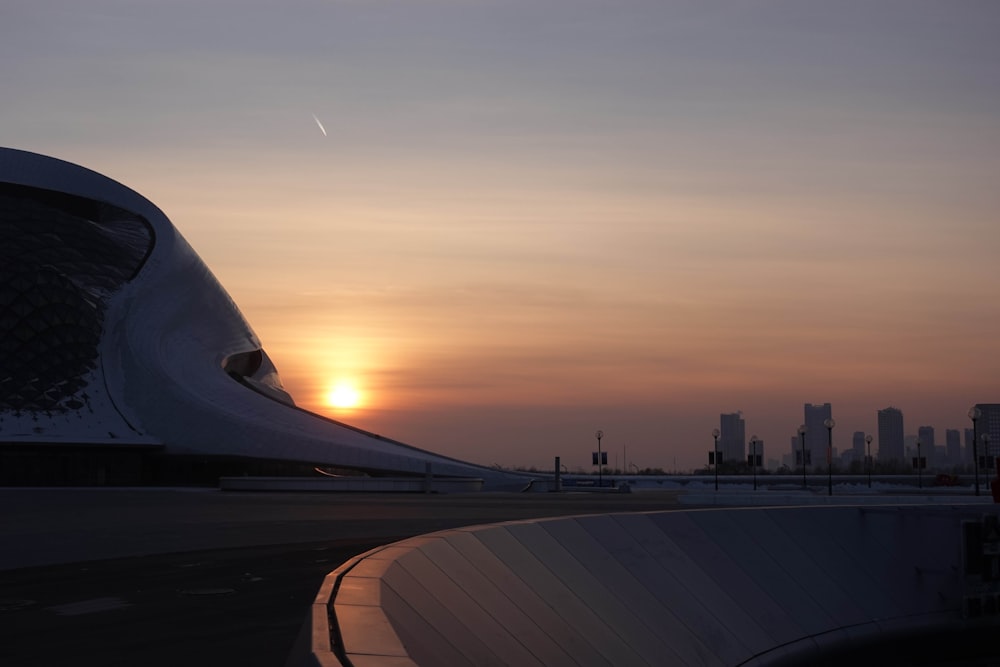 the sun is setting behind a modern building