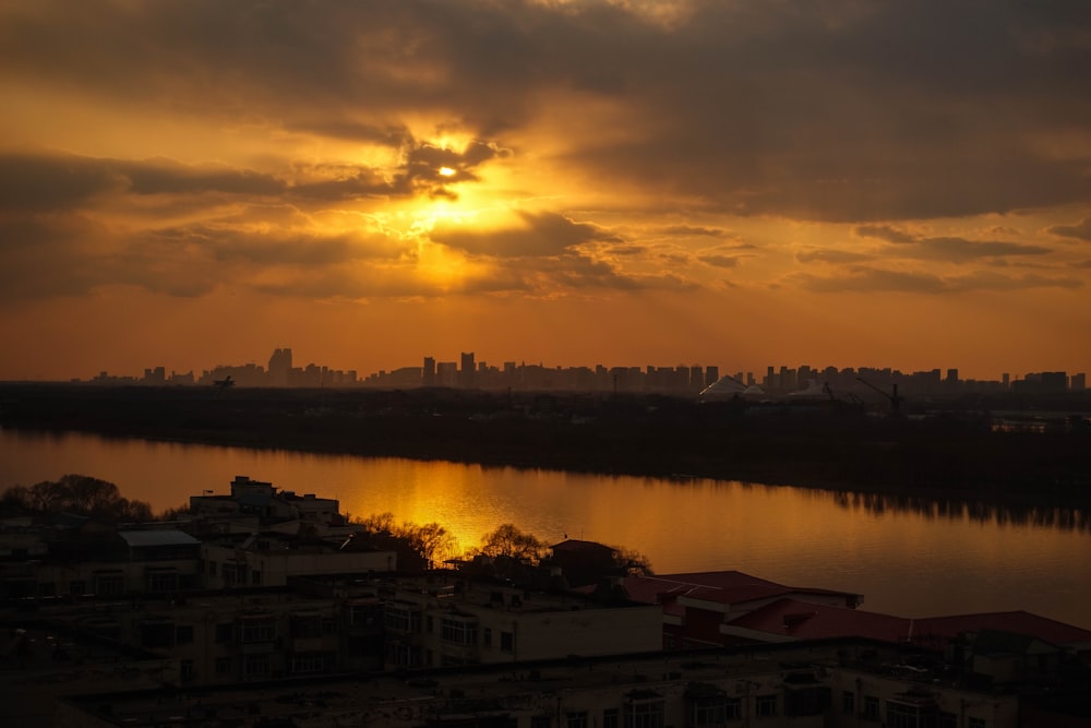 the sun is setting over a city and a body of water