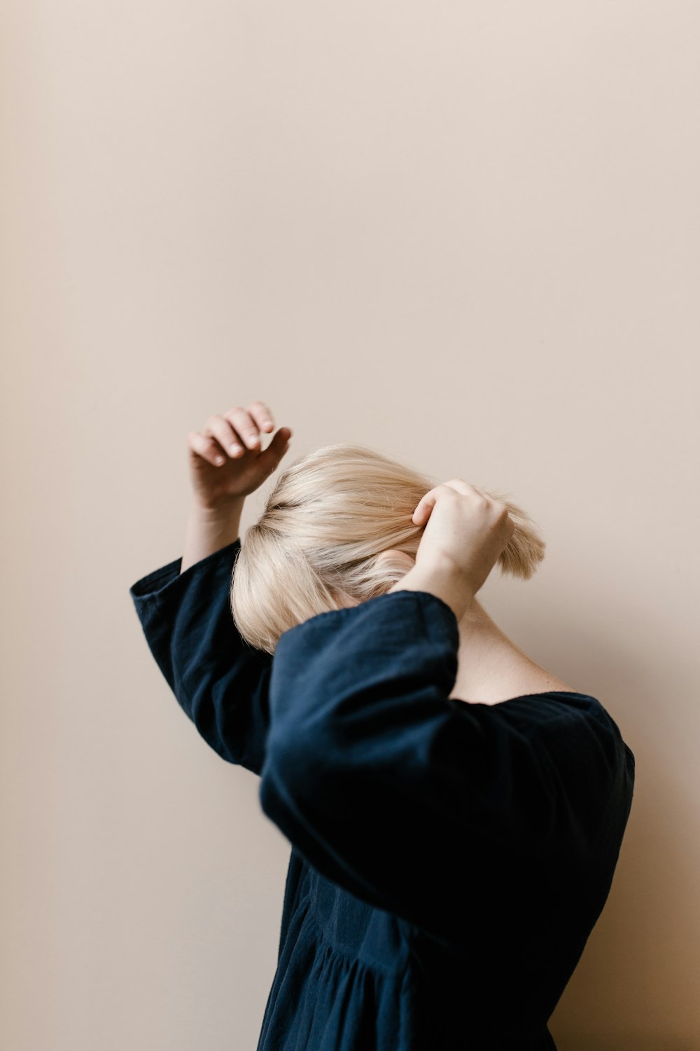 a woman with blonde hair is standing against a wall