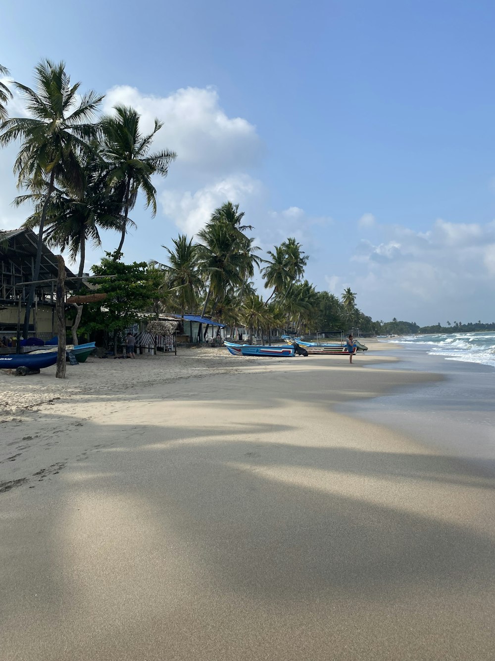 a sandy beach with boats and palm trees