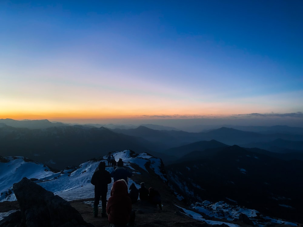 a group of people standing on top of a snow covered mountain