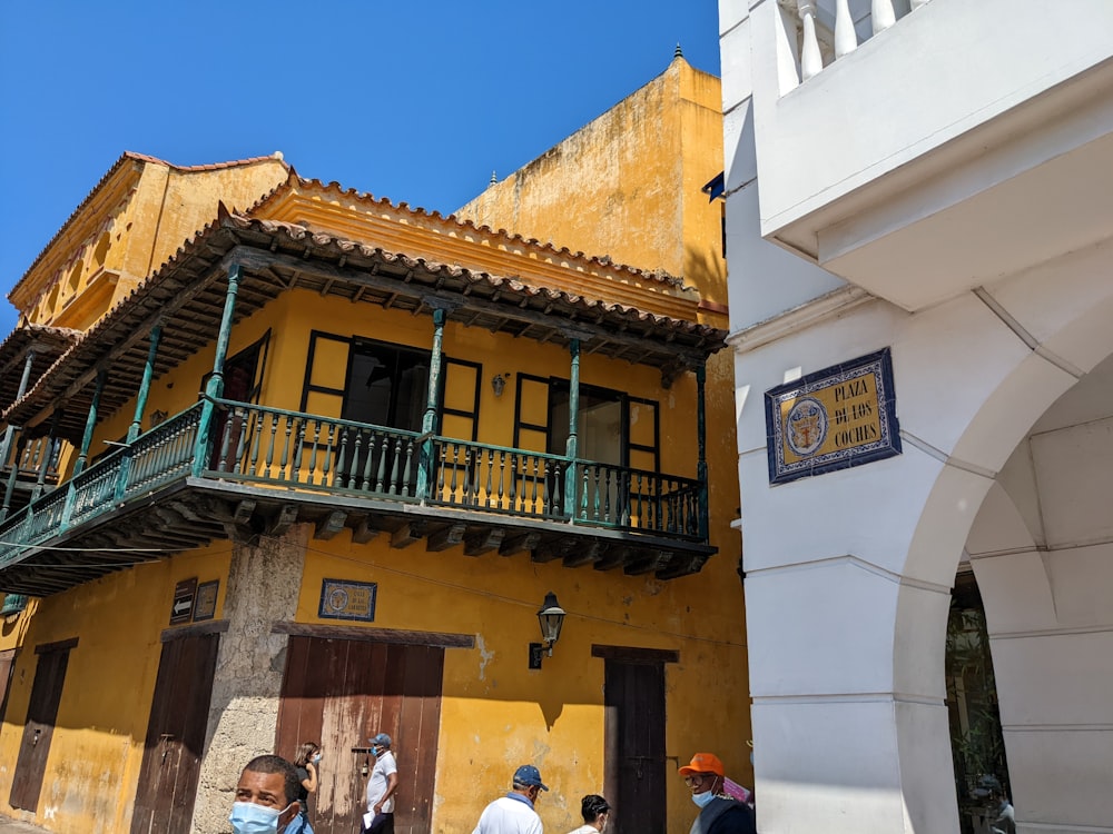 a group of people standing outside of a yellow building