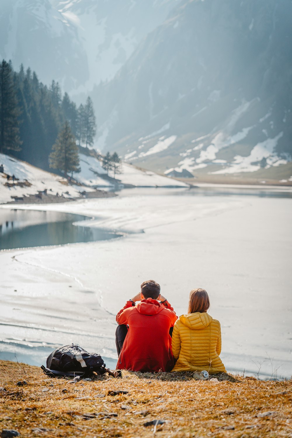 a couple of people sitting on top of a snow covered field