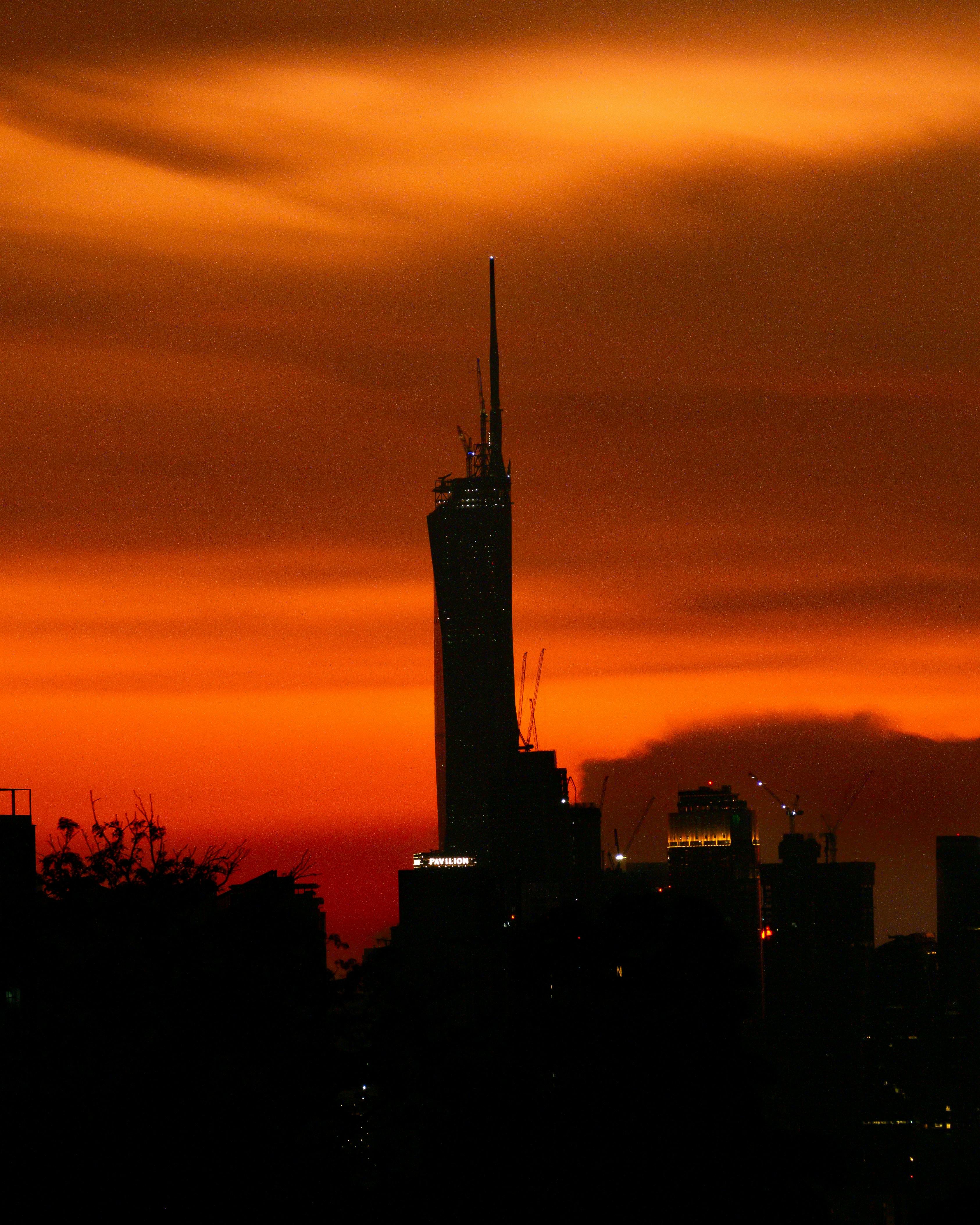 a very tall building towering over a city at sunset