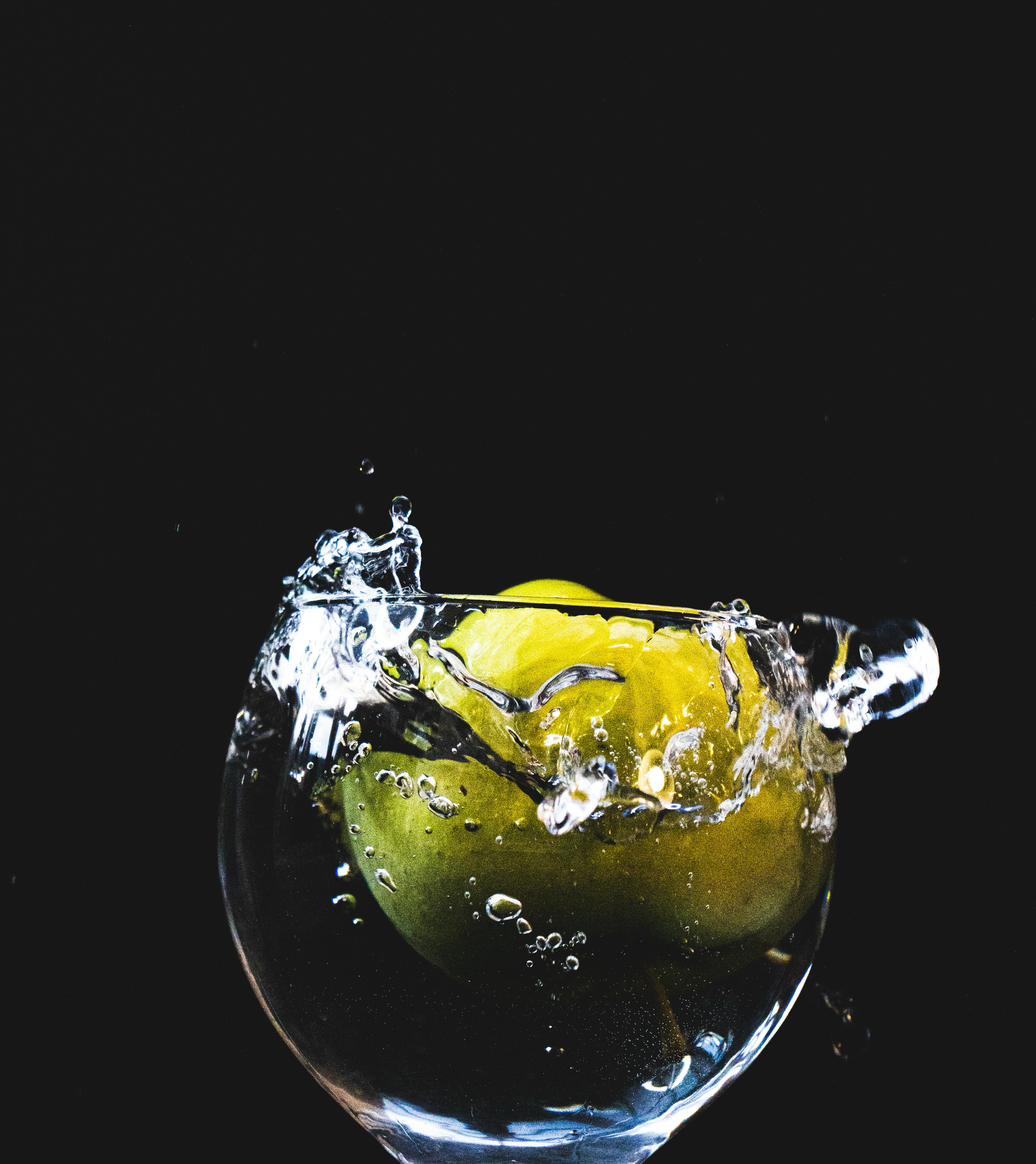 a glass filled with water and a green apple