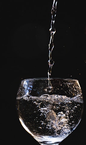 A close-up of crystal-clear water pouring from a modern water filter into a glass.