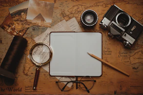 an open notebook, magnifying glass, a pen, and a pair of