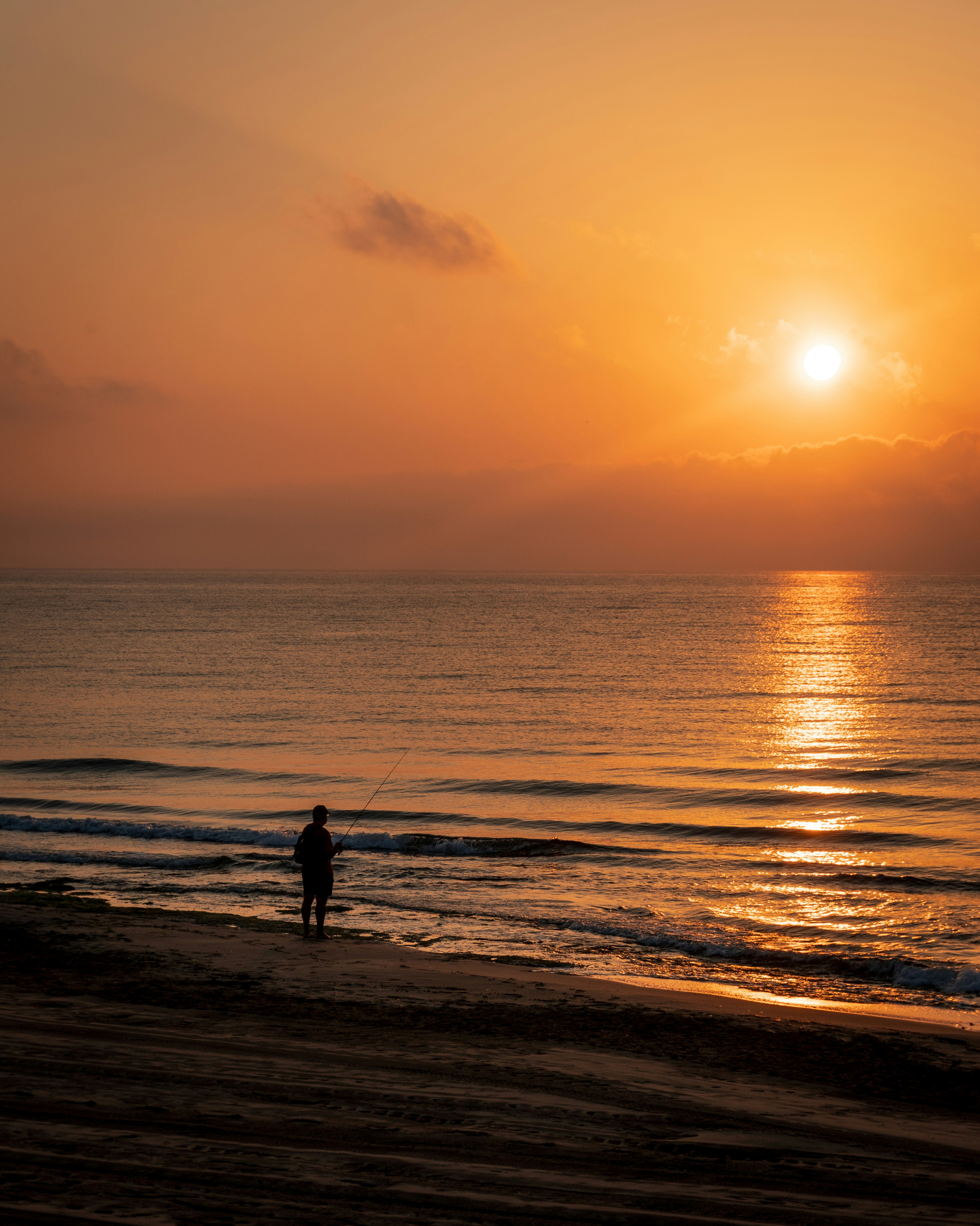 a person standing on a beach at sunset