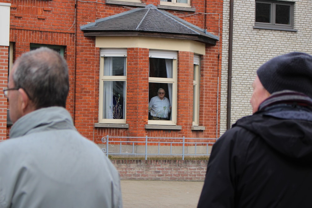 a couple of men standing in front of a red brick building