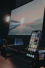 a cell phone sitting on top of a desk next to a monitor