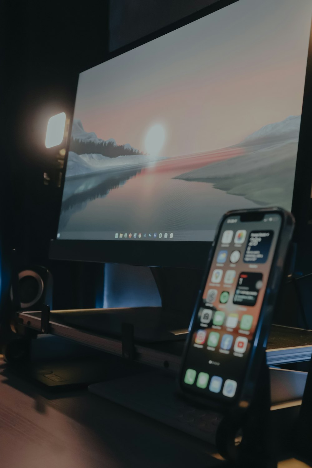 a cell phone sitting on top of a desk next to a monitor