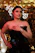 A stylish woman smiling confidently while wearing a sleek black dress and gold accessories, embodying modern luxury.