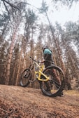 Mountain bike helmet resting on a rugged trail with forest background.