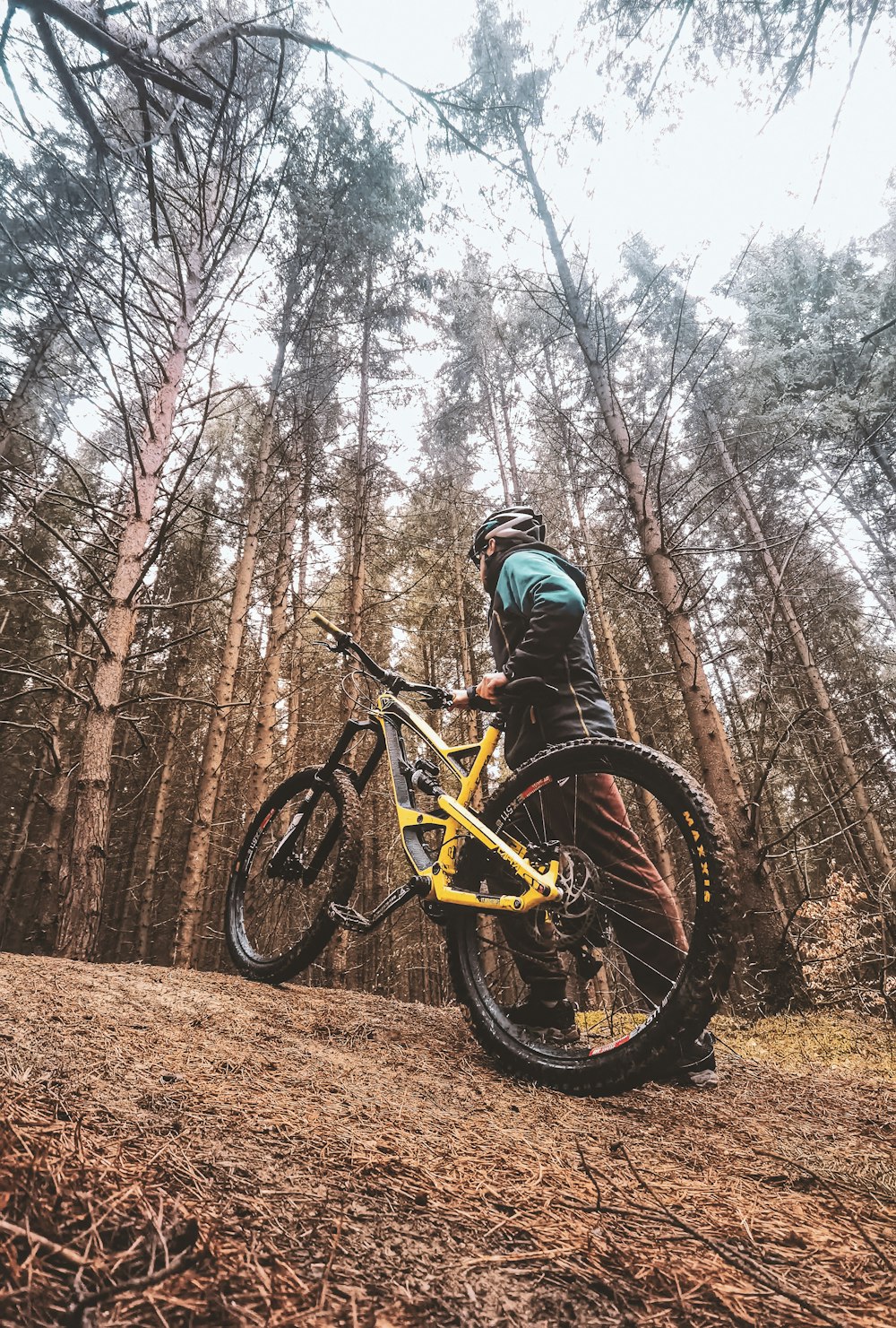 a man standing next to a yellow bike in a forest