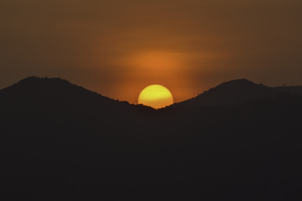 the sun is setting over a mountain range