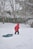 a little boy playing in the snow with a sled