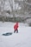 a little boy playing in the snow with a sled