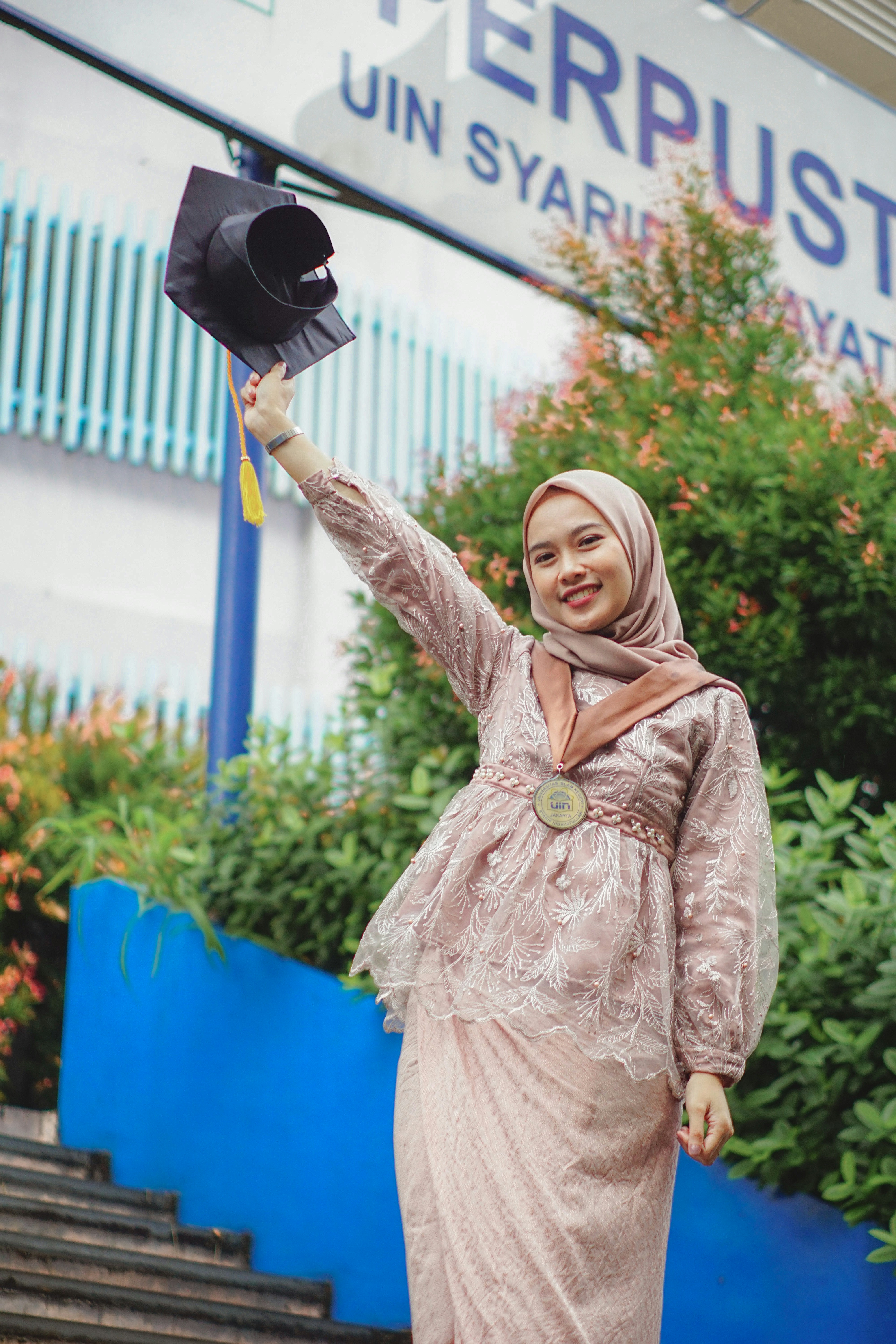 Seorang wanita berjilbab memegang topi