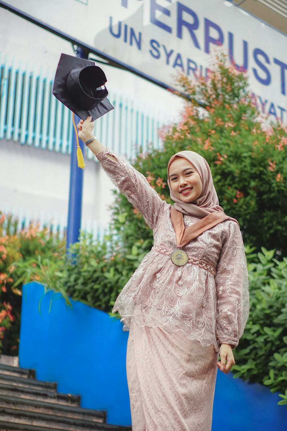 a woman in a hijab is holding a hat