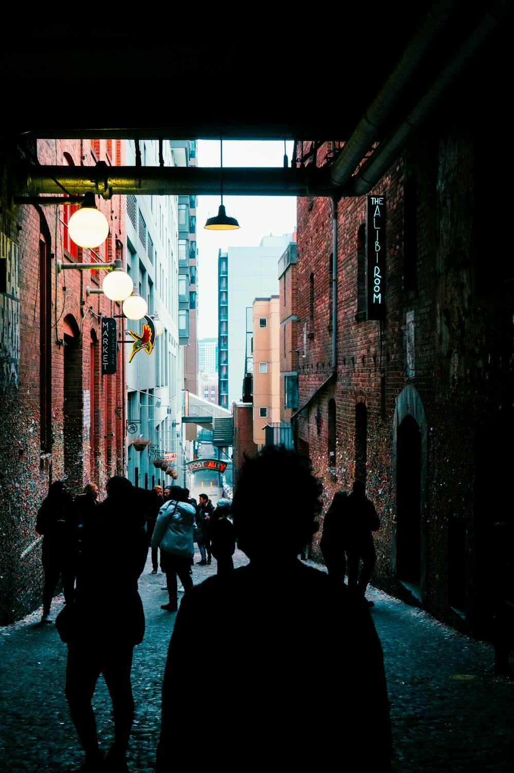 a group of people walking down a street next to tall buildings