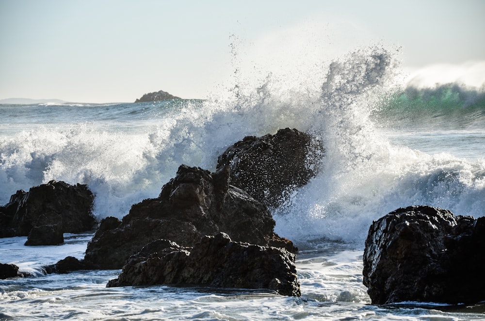 a large wave crashing over rocks in the ocean