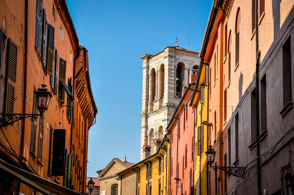 a narrow street with buildings and a clock tower in the background