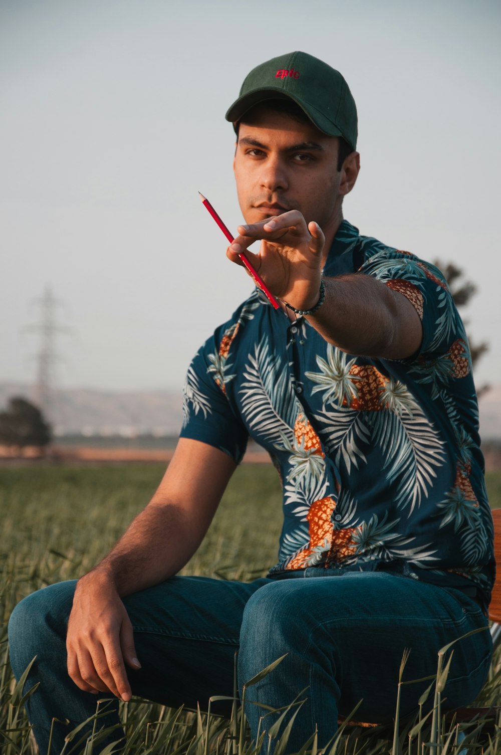 a man sitting in a field holding a pair of scissors
