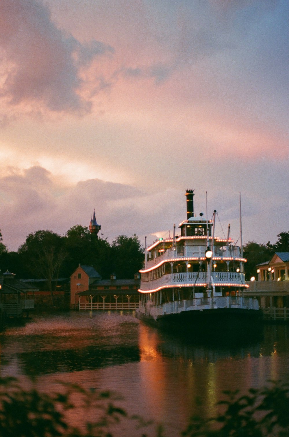 a large boat floating on top of a river under a cloudy sky